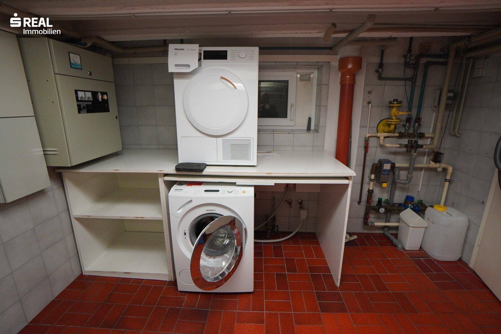 Waschküche mit Waschmaschine, Trockner und Fliesenboden.