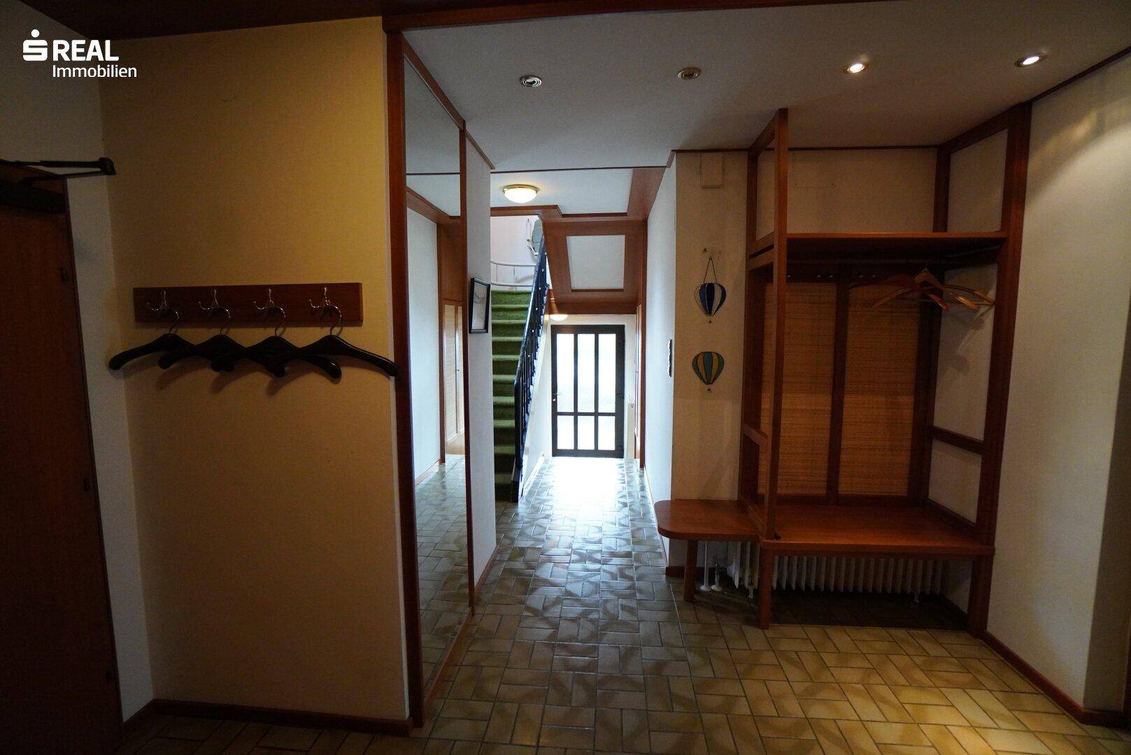 Geräumiger Flur mit Fliesenboden, Garderobe und Spiegelwand.
