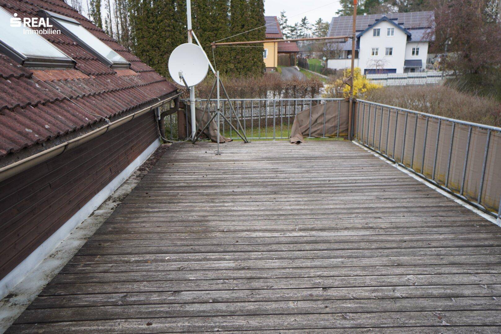 Große Dachterrasse mit Holzbelag, Satellitenschüssel und Blick auf die Nachbarschaft.