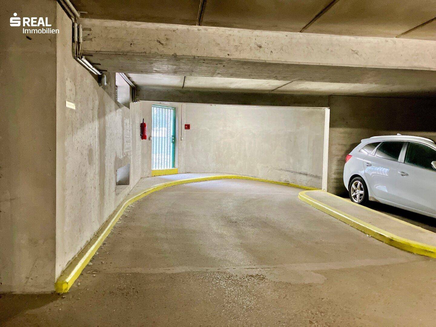 Einfahrt zur Tiefgarage mit Rampe und Betonwänden.