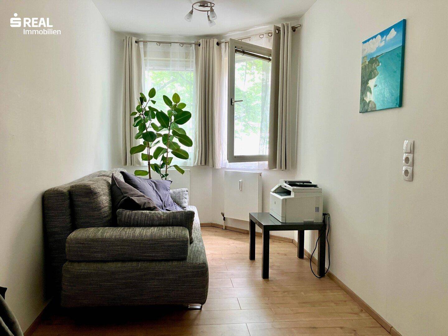 Kleines Arbeitszimmer mit Sofa, Schreibtisch und Fenster, ideal für Home-Office.