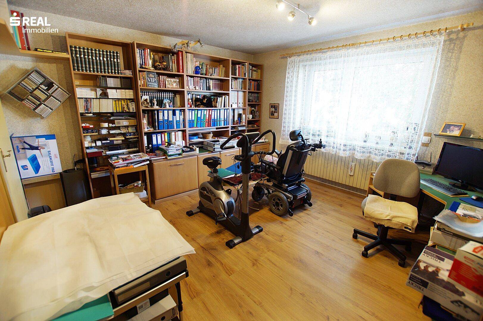 Geräumiges Arbeitszimmer mit großem Bücherregal, Holzboden und Fenster, ideal für Home-Office.