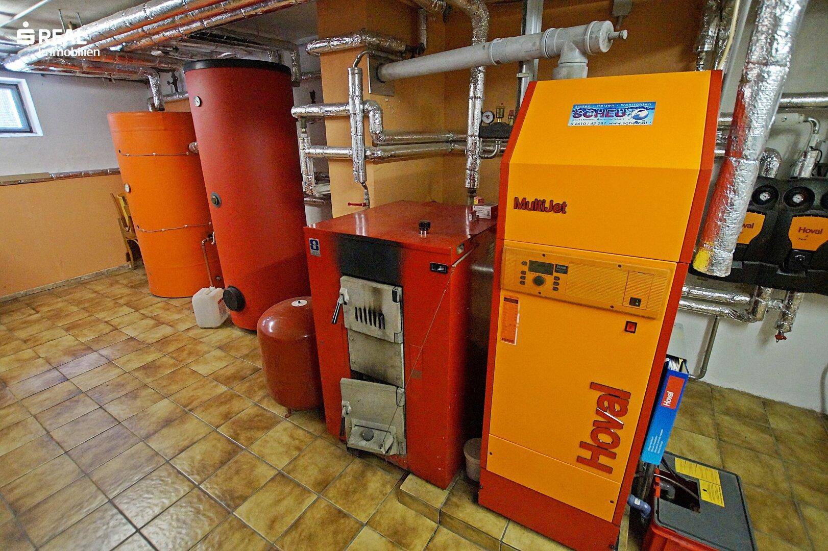 Heizraum mit moderner Heizungsanlage und Warmwasserspeichern im Kellerbereich.