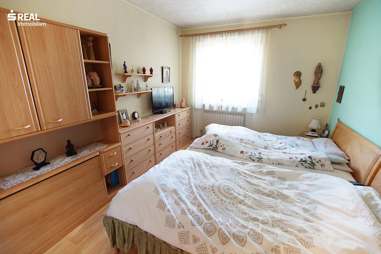 Gemütliches Schlafzimmer mit zwei Betten, Holzmöbeln und Fenster, hell und funktional.