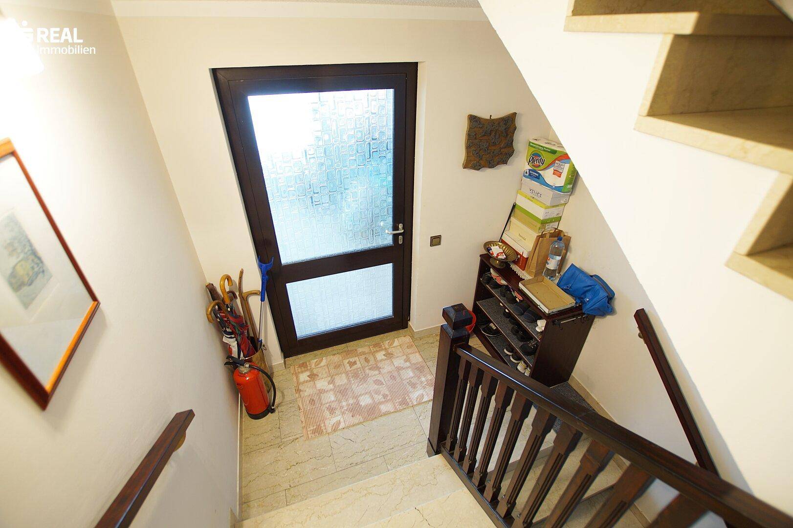 Eingangsbereich mit Treppe und Haustür, hell und funktional gestaltet.