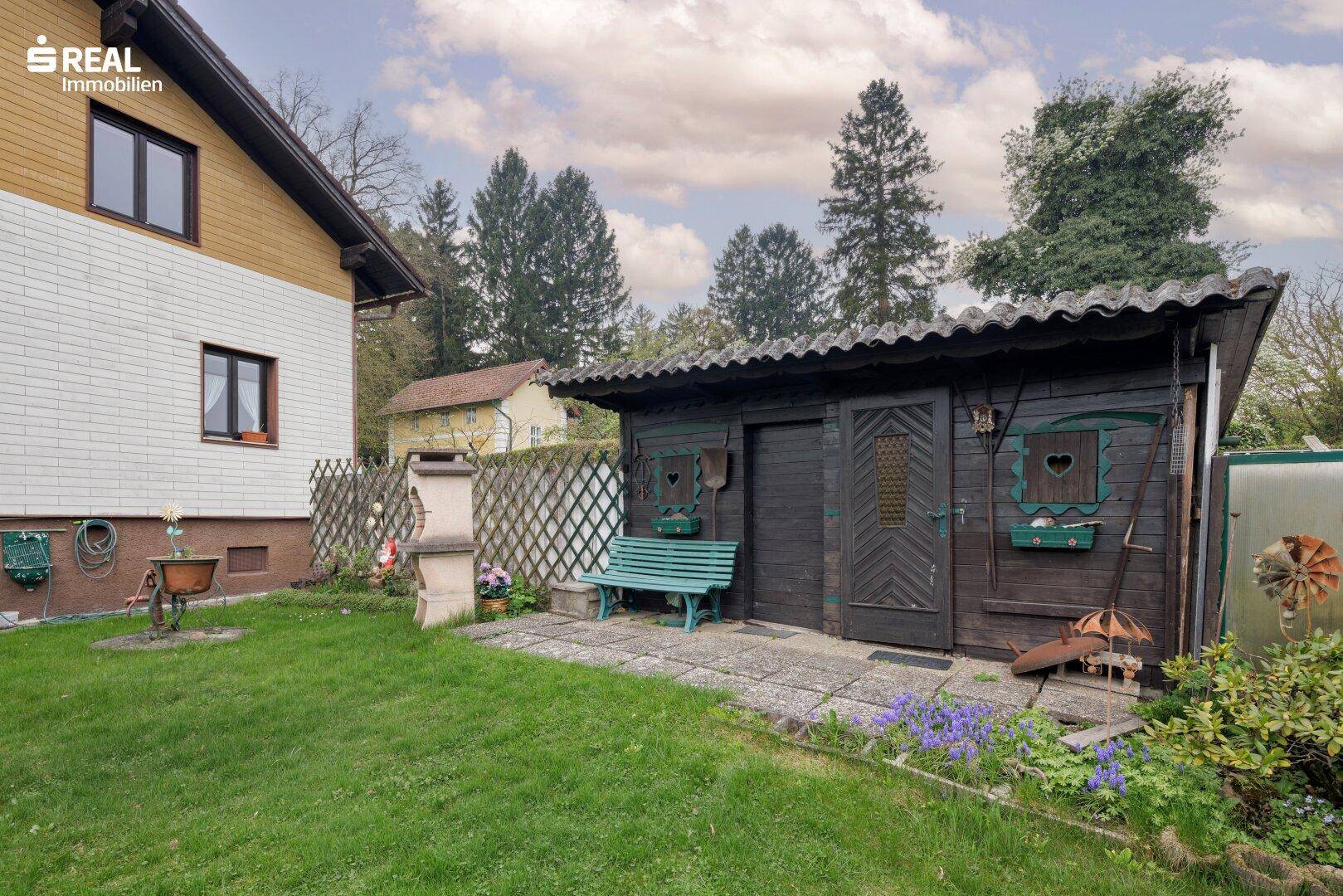 Rustikales Gartenhaus mit Sitzbank und Grillplatz neben dem Wohnhaus.