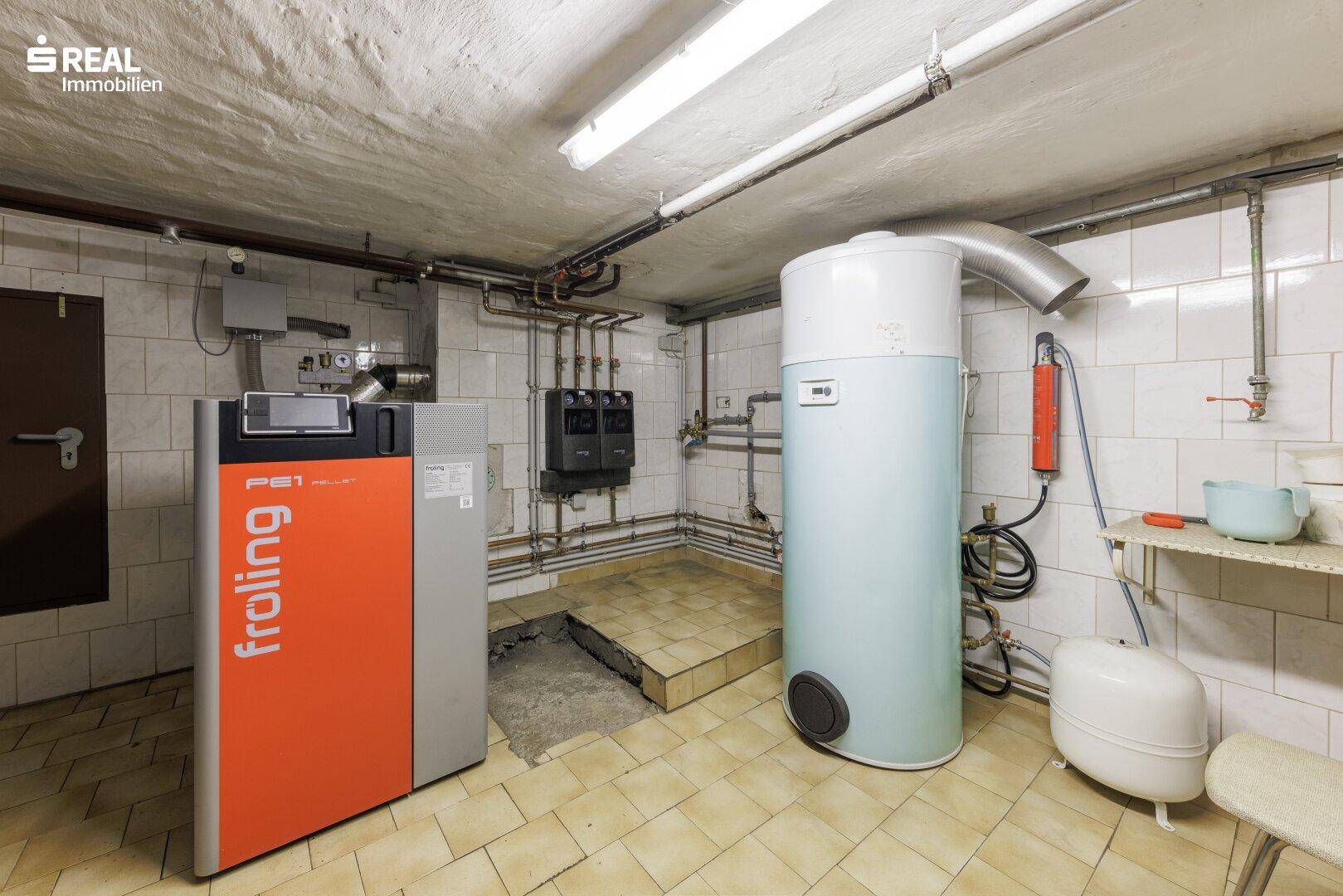 Heizungsraum im Keller mit moderner Pelletheizung und Warmwasserspeicher.