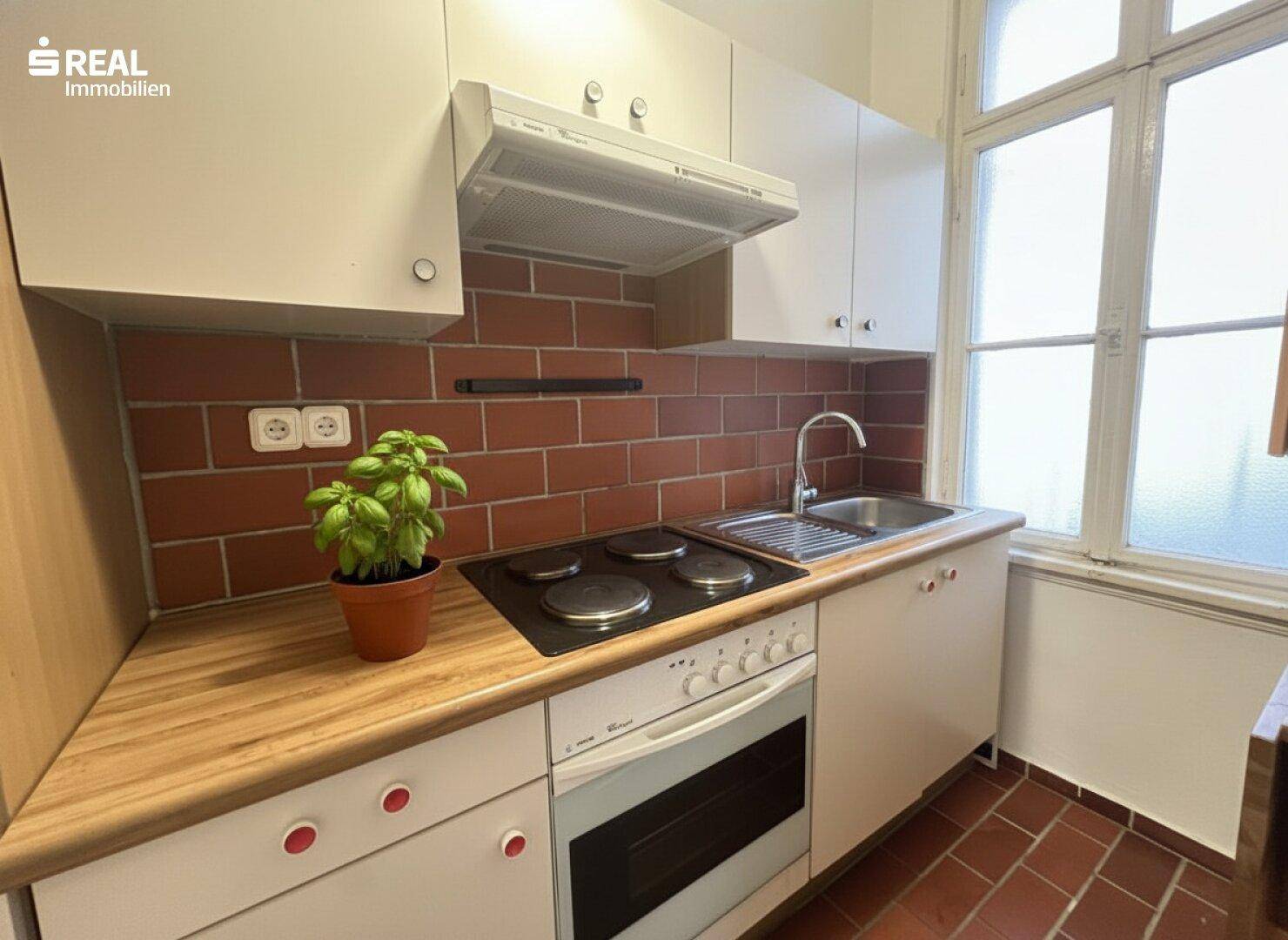 Kleine Küche mit roten Fliesen als Spritzschutz, Holz-Arbeitsplatte und integriertem Herd.