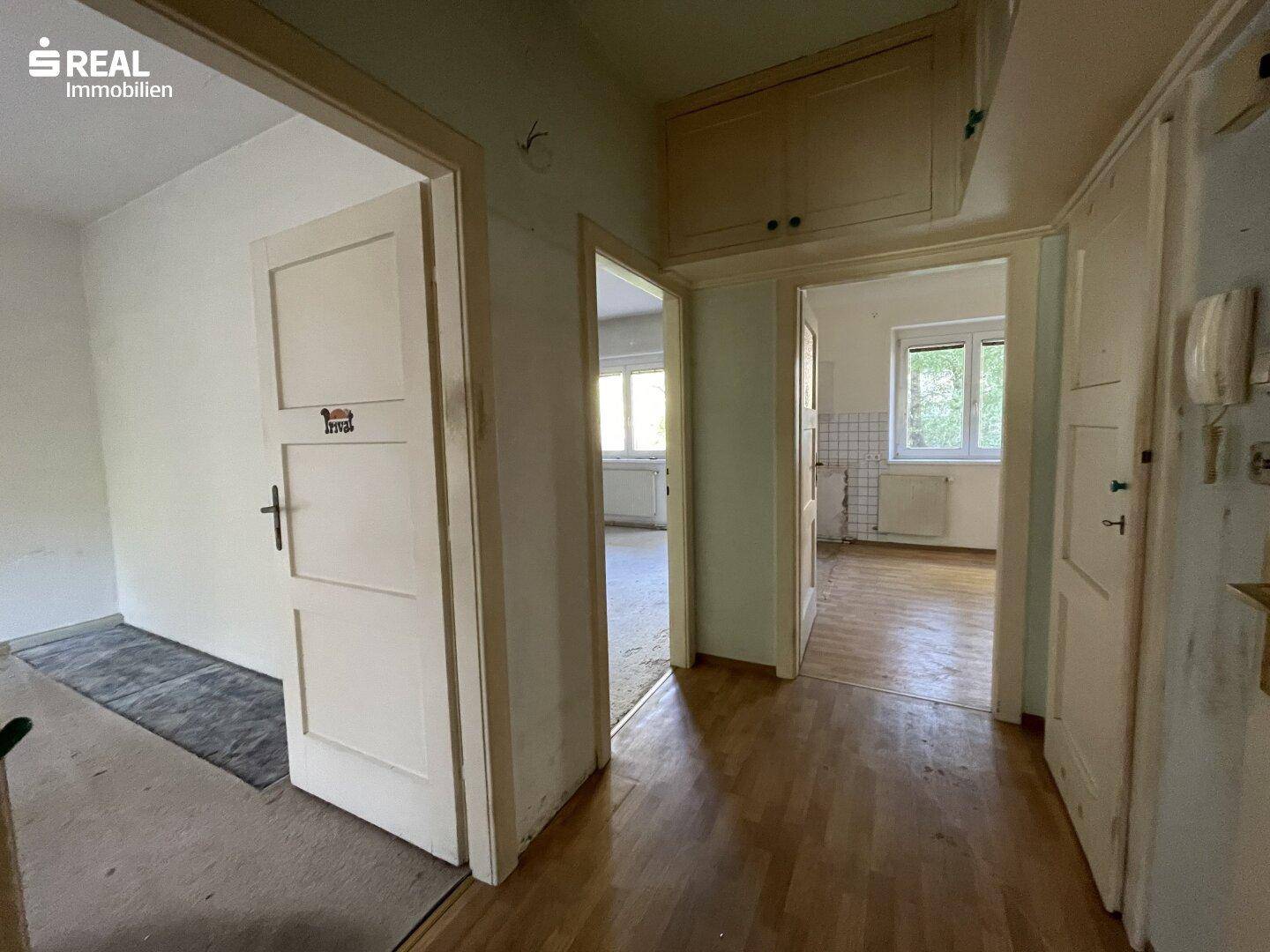 Heller Flur mit Holzboden und mehreren Türen, der verschiedene Räume verbindet.