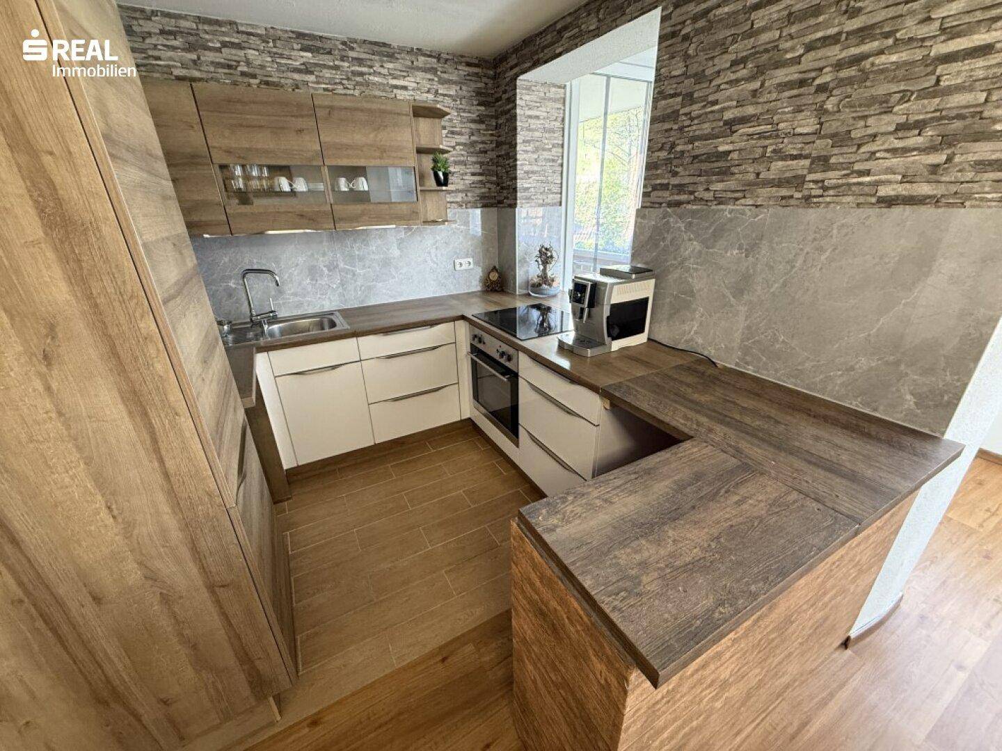 Moderne Einbauküche mit Holzoptik-Fronten, Steinwand-Akzent und integrierten Geräten.