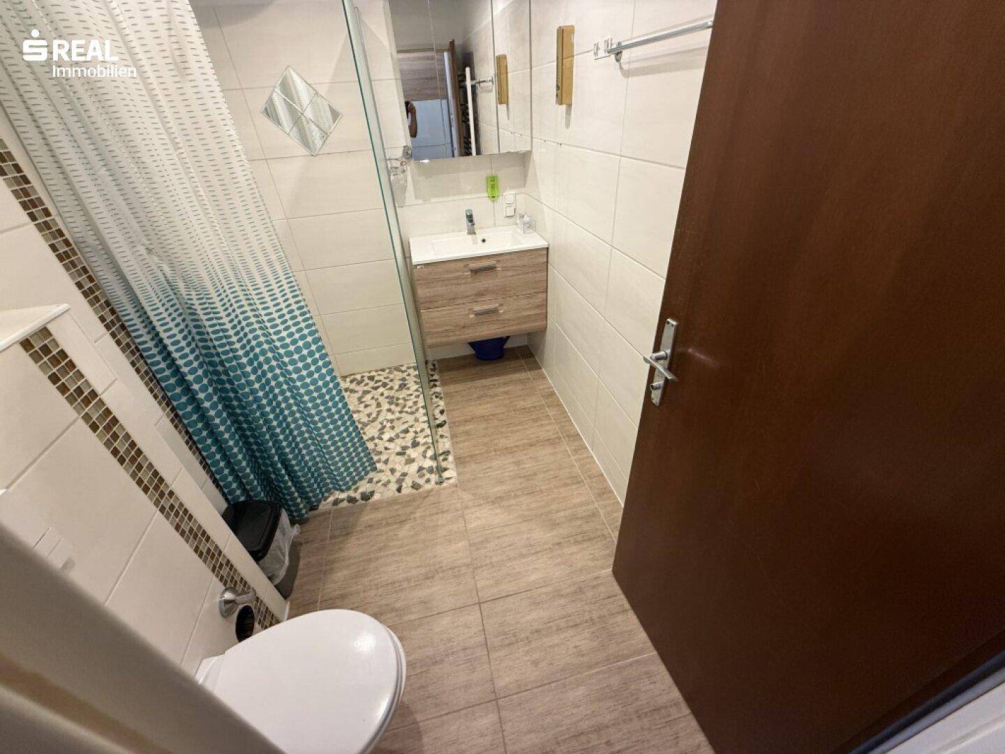 Modernes Badezimmer mit Duschkabine, WC und Waschbecken.