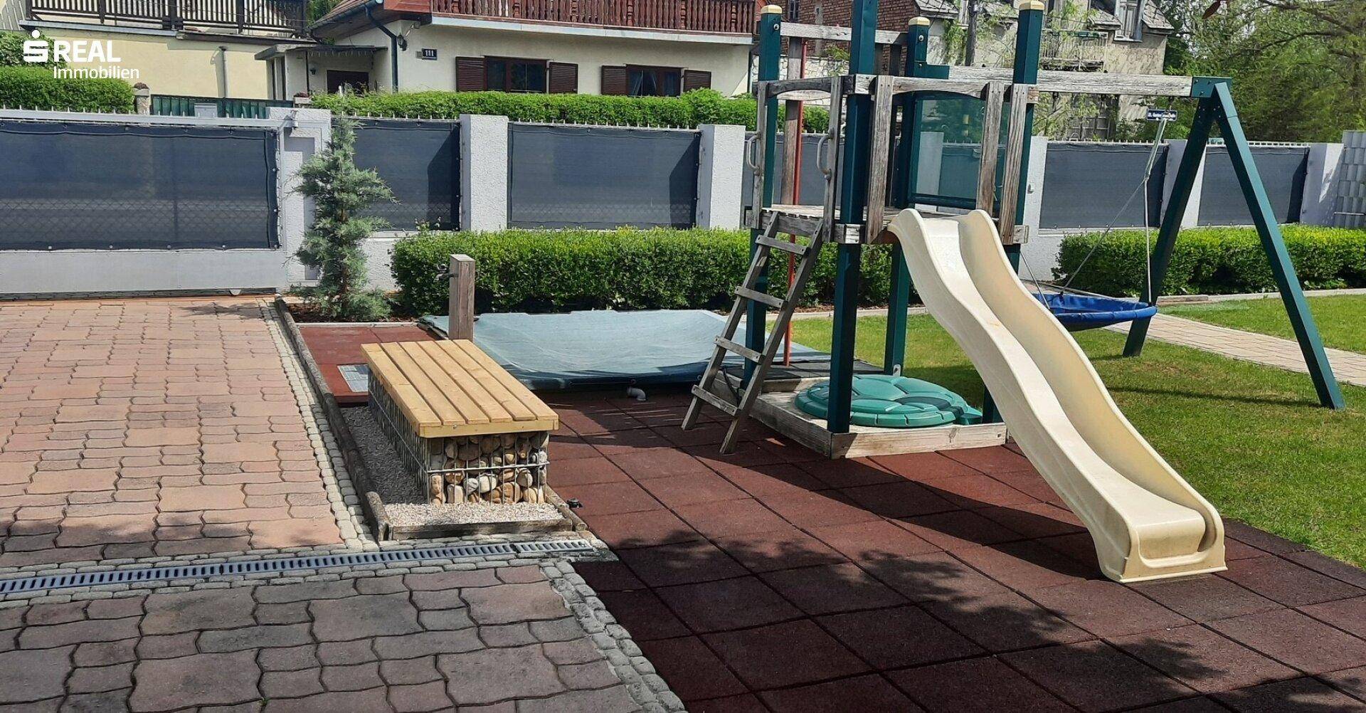 Großer Gartenbereich mit Kinderspielplatz, Sitzbank und überdachtem Whirlpool.