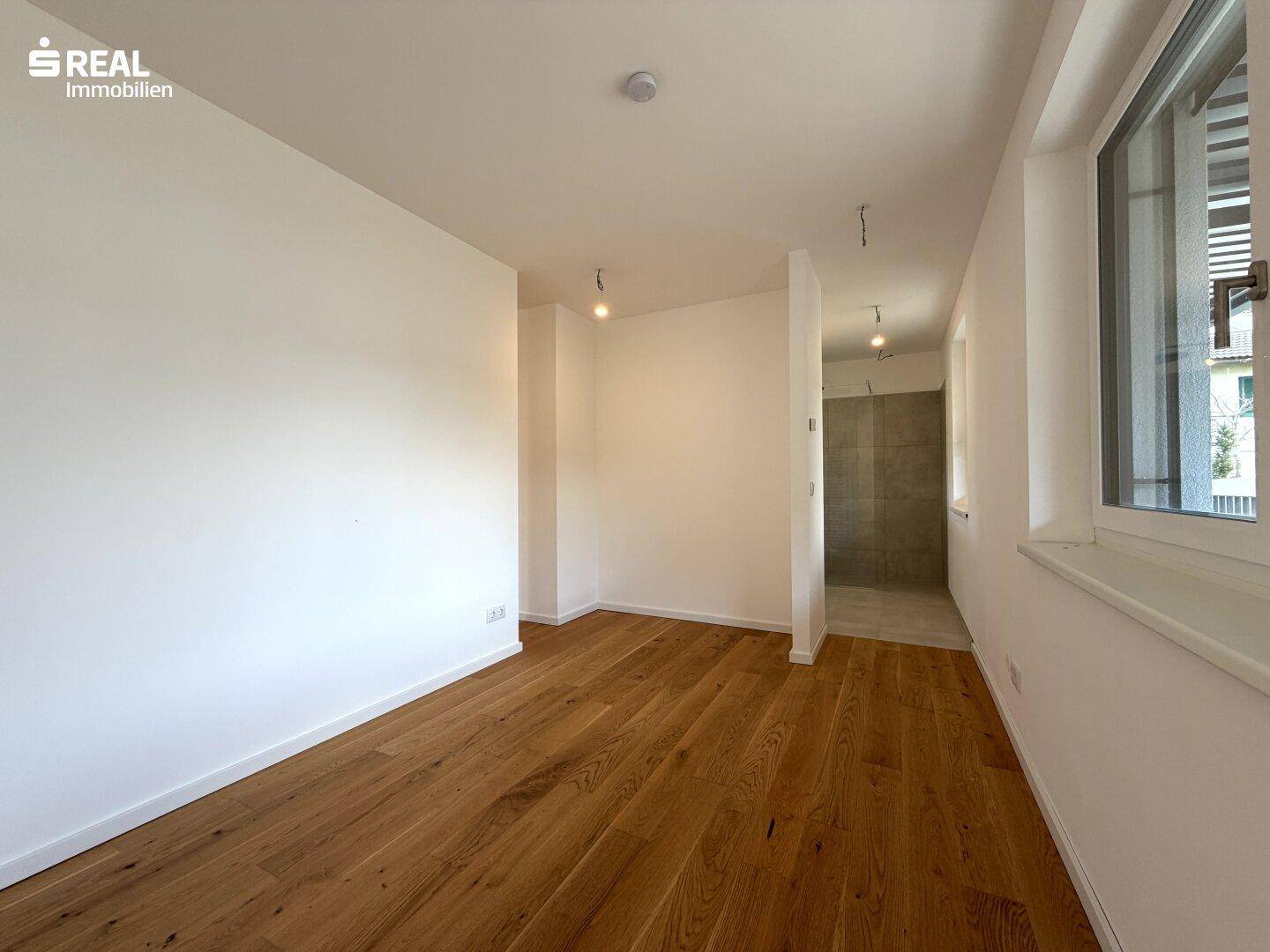 Helles Zimmer mit Holzboden und weißen Wänden, bereit für individuelle Gestaltung.