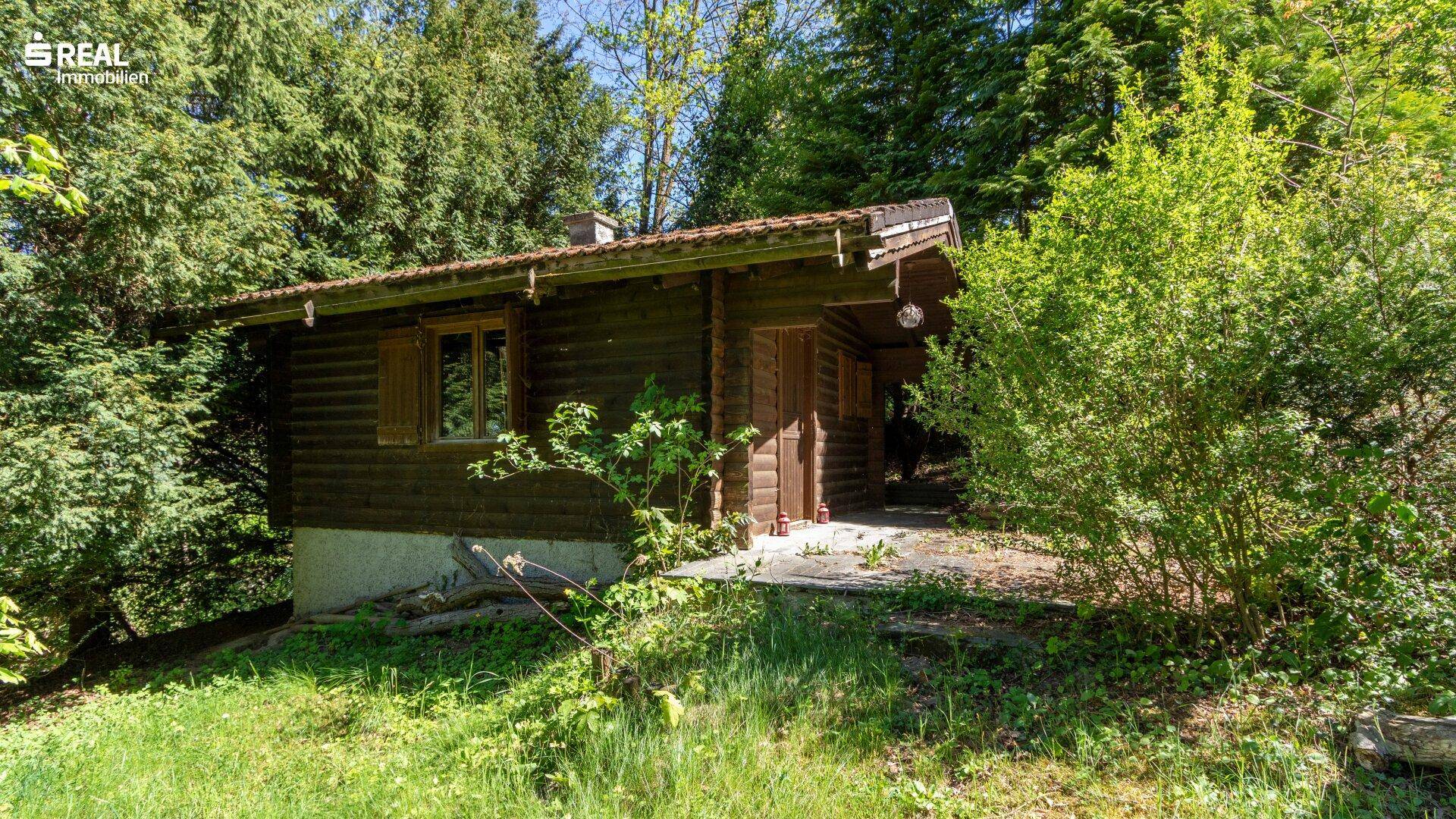 Rustikales Gartenhaus aus Holz, eingebettet in die grüne Umgebung.