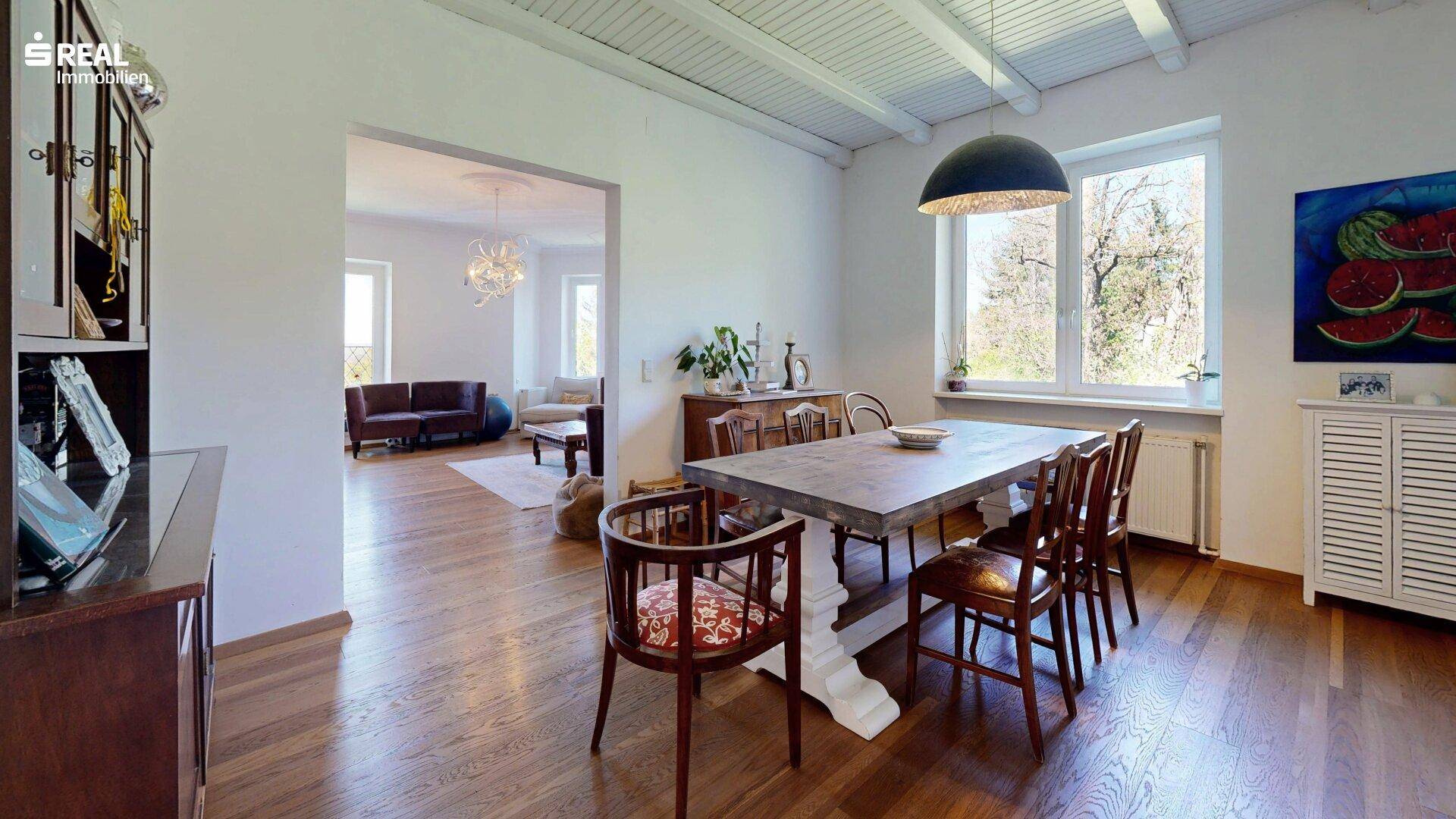 Heller Essbereich mit Holzboden und Blick in das angrenzende Wohnzimmer.