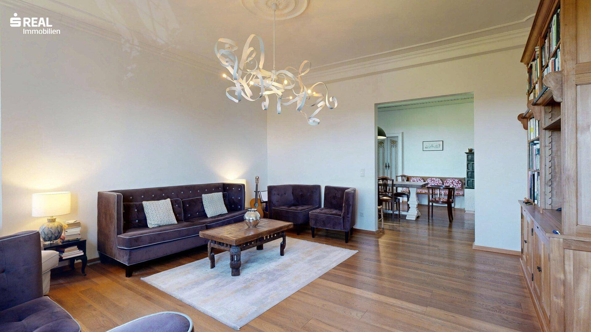 Geräumiges Wohnzimmer mit Holzboden und Blick in den angrenzenden Essbereich.