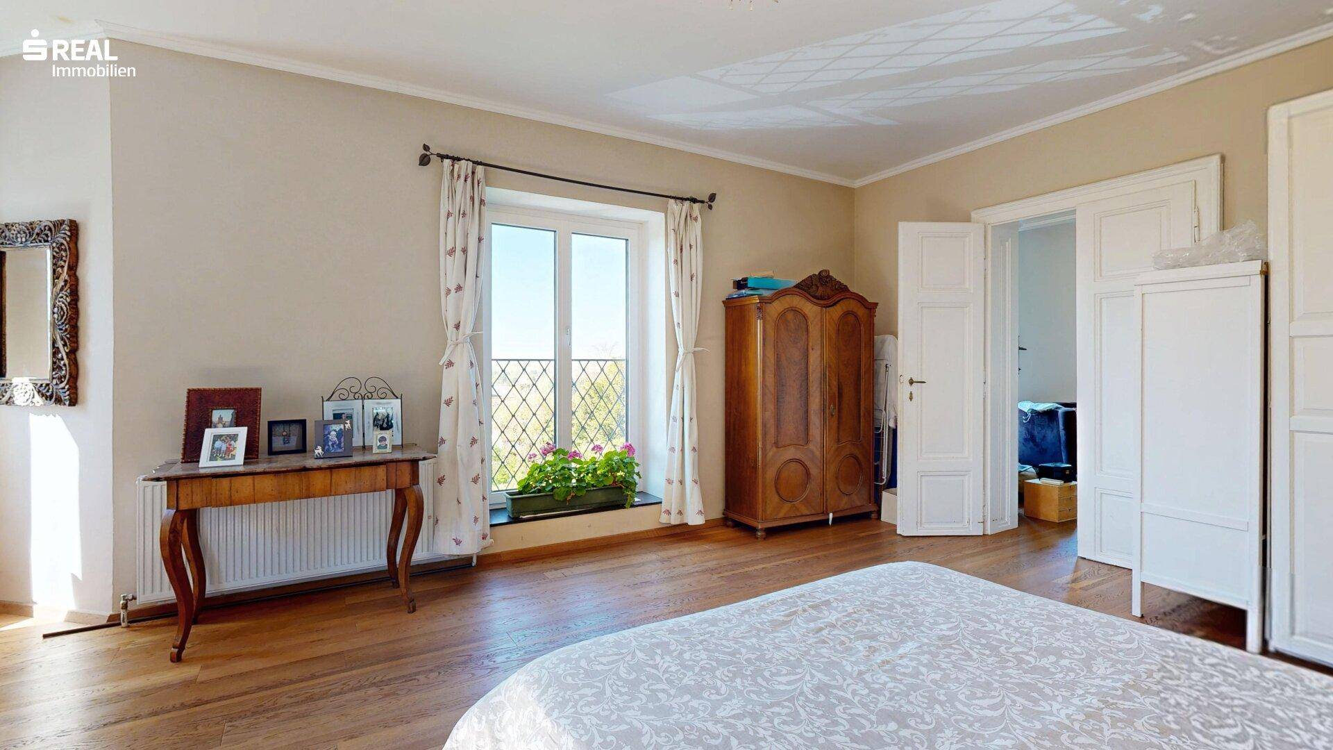 Geräumiges Schlafzimmer mit Holzboden, antiken Möbeln und viel Tageslicht.
