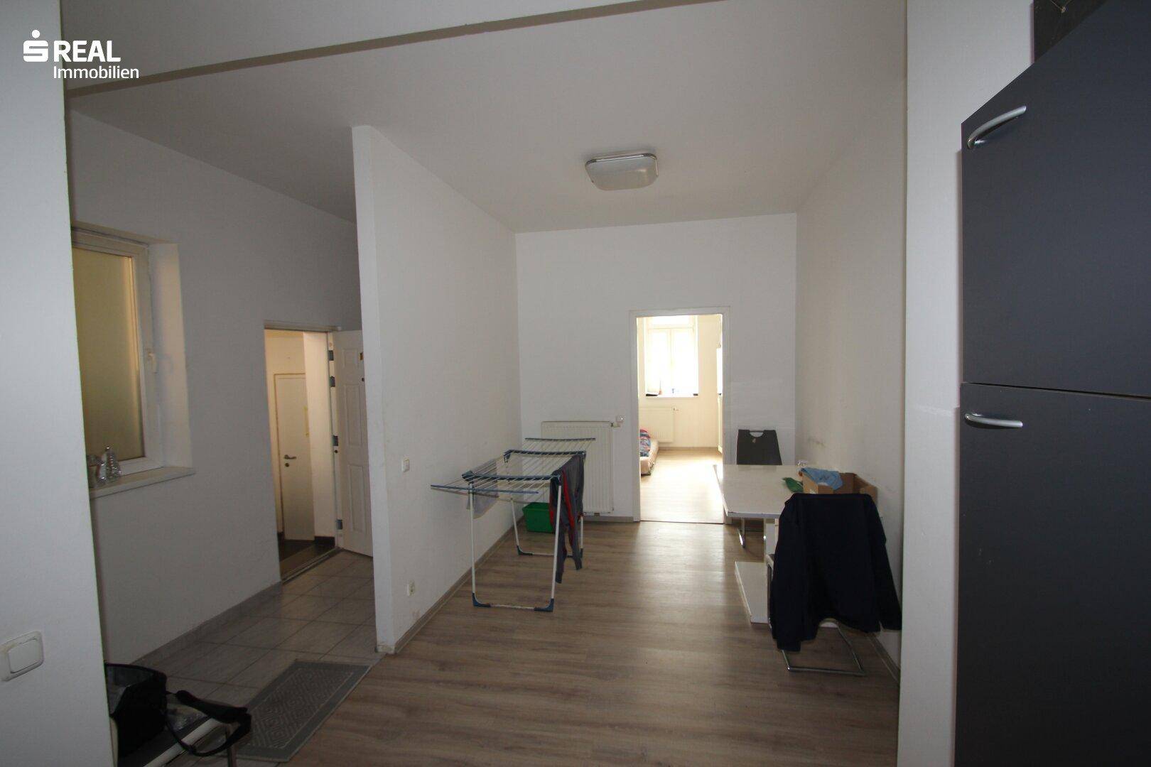 Heller Flur mit Holzboden, Wäscheständer und Zugang zu weiteren Räumen, funktional gestaltet.