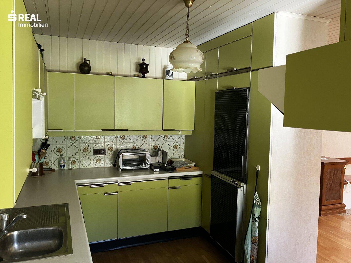 Grüne Küche im Vintage-Stil mit Holzdecke und älteren Geräten, die eine Renovierung benötigt.