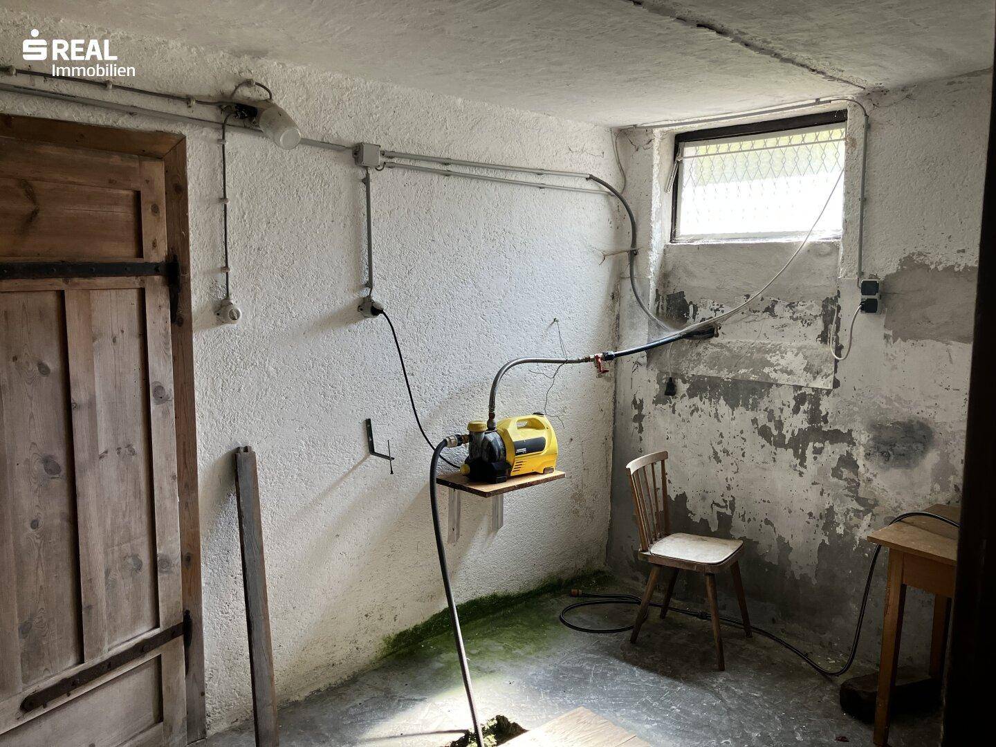 Kellerraum mit Fenster, Wasserpumpe und einfacher Ausstattung, ideal als Technik- oder Abstellraum.