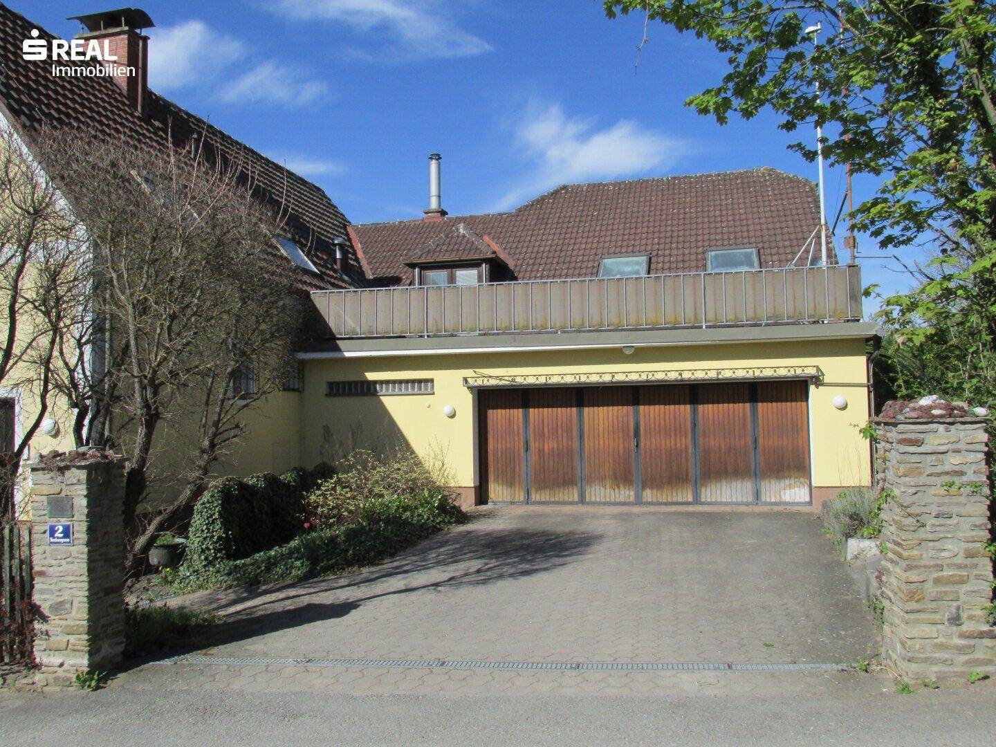 Vorderansicht des Hauses mit großer Garage und darüberliegender Terrasse.