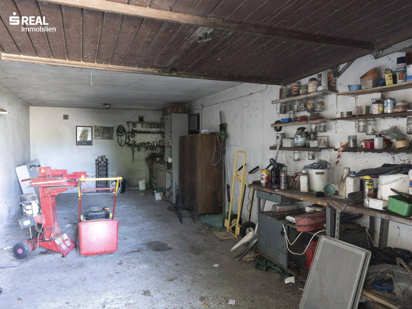 Geräumige Garage oder Werkstatt mit vielen Regalen, Werkzeugen und Geräten für verschiedene Arbeiten.