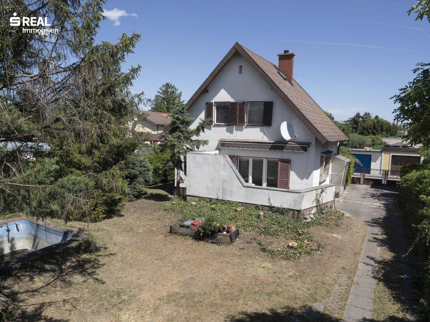Vogelperspektive des Hauses mit Garten, Rasenfläche und einem kleinen Pool im Vordergrund.
