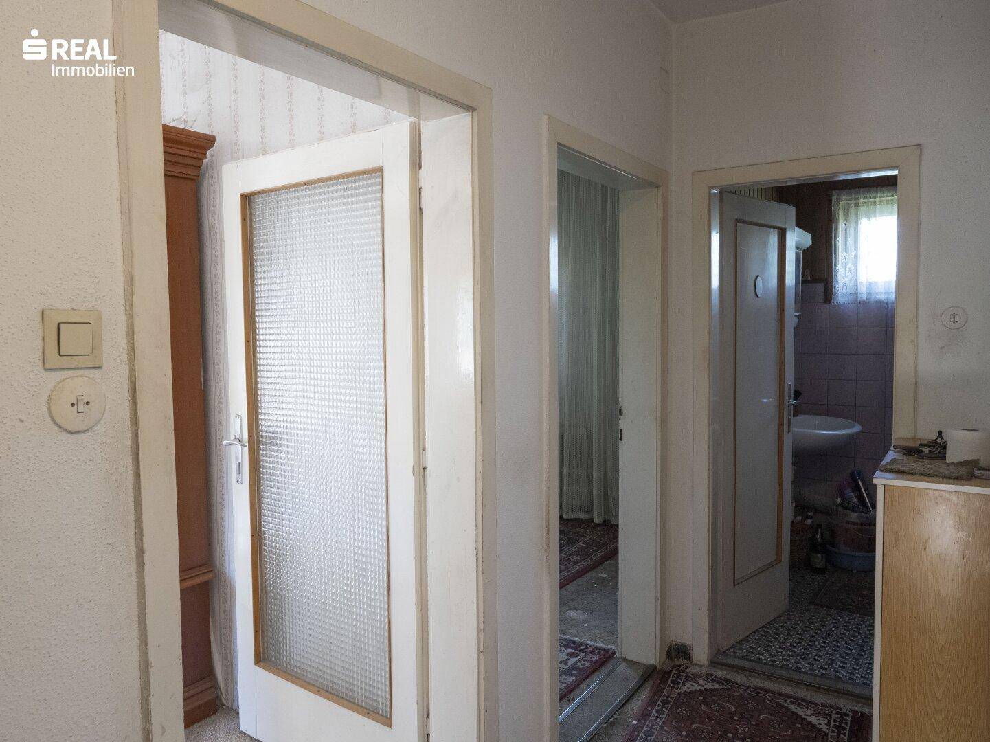 Flur mit mehreren Türen, darunter eine mit Milchglas, und Blick in angrenzende Räume.