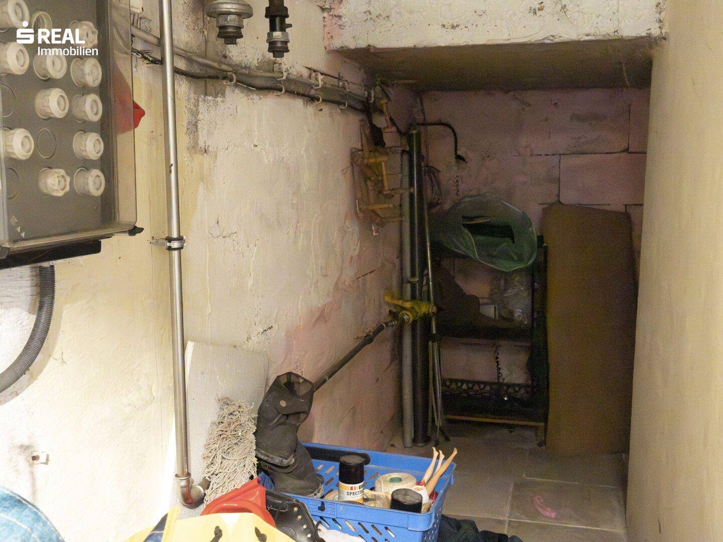 Abstellbereich im Keller mit verschiedenen Gegenständen und sichtbaren Installationen.