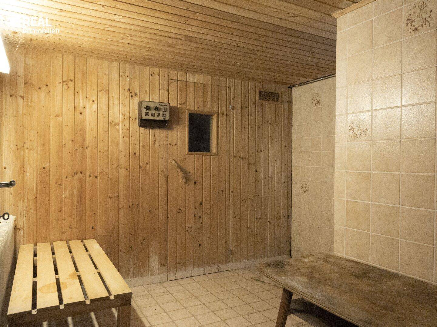Sauna mit Holzvertäfelung, Bänken und einem Bedienfeld für die Temperatur.