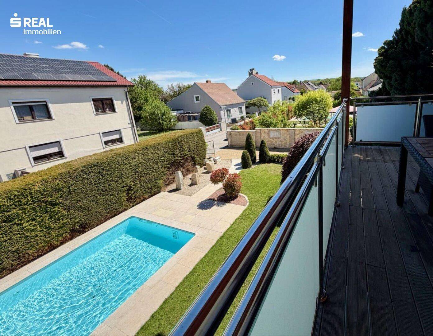 Balkon mit Glasgeländer bietet einen schönen Blick auf den Pool und die umliegende Nachbarschaft.