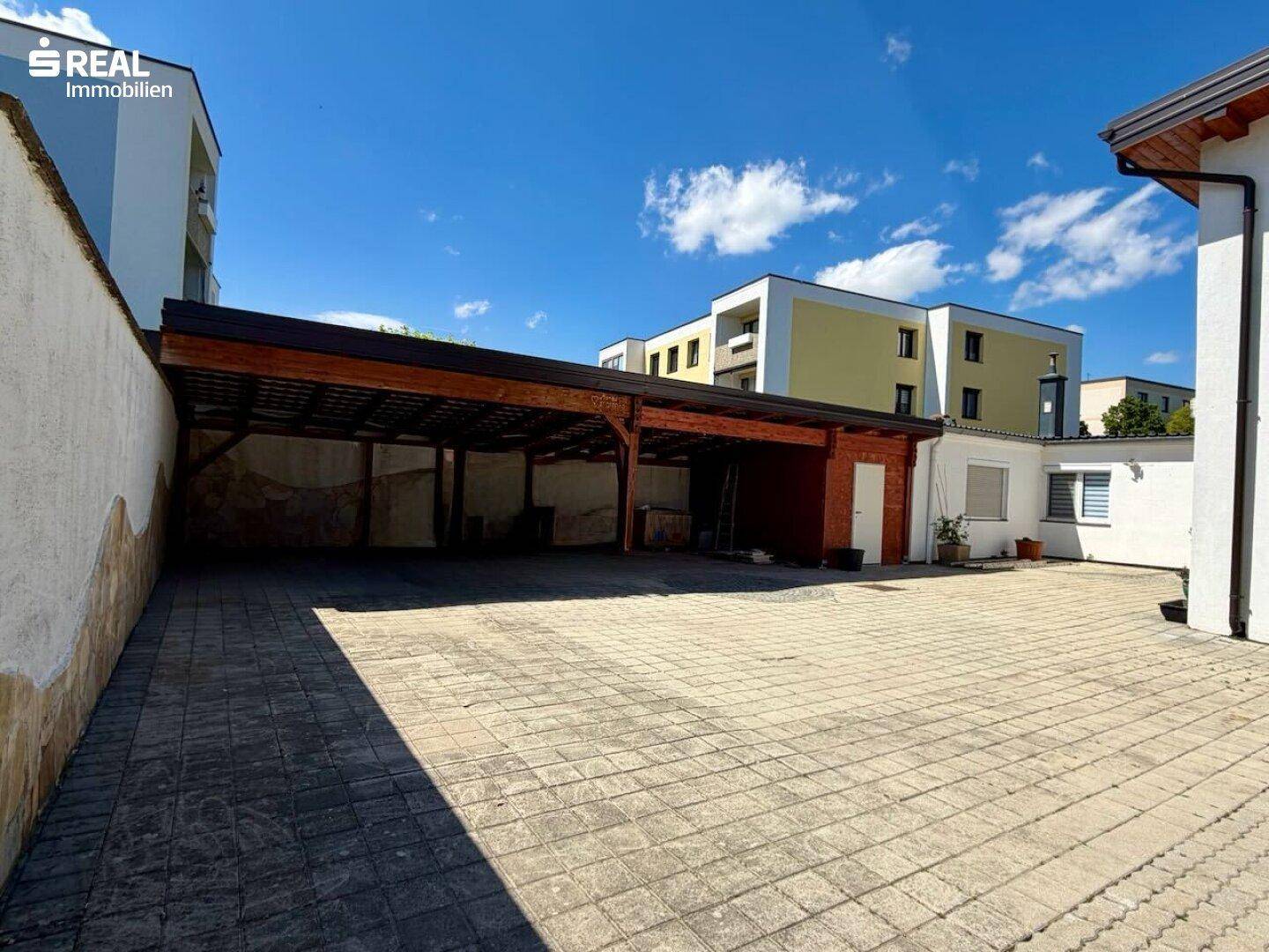 Großer gepflasterter Hofbereich mit überdachtem Carport und weiteren Parkmöglichkeiten.