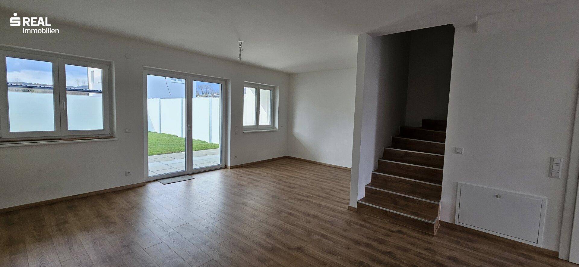 Heller Wohnbereich mit Laminatboden, Treppe und direktem Zugang zur Terrasse und zum Garten.