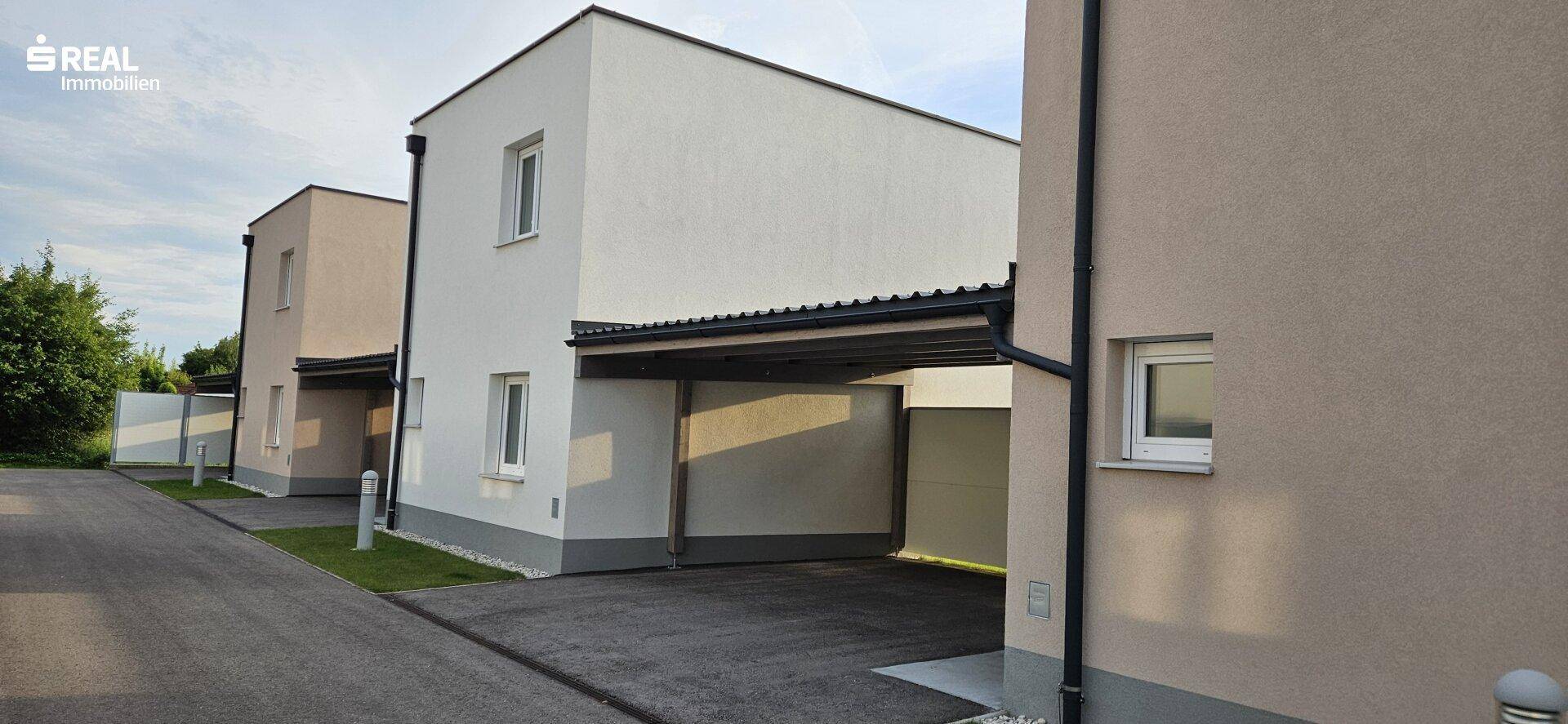 Reihe moderner Reihenhäuser mit Carports und gepflegten Vorgärten in einer Neubausiedlung.