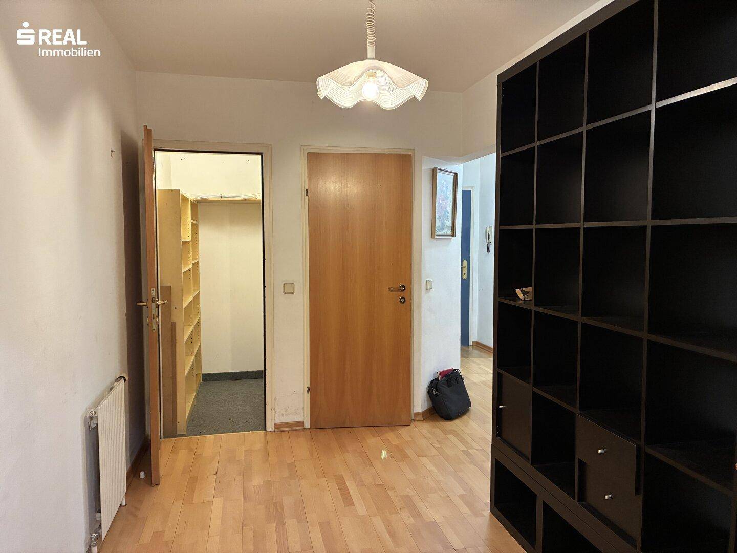 Flur mit Holzboden, großem Regal und Zugang zu einem praktischen Abstellraum.