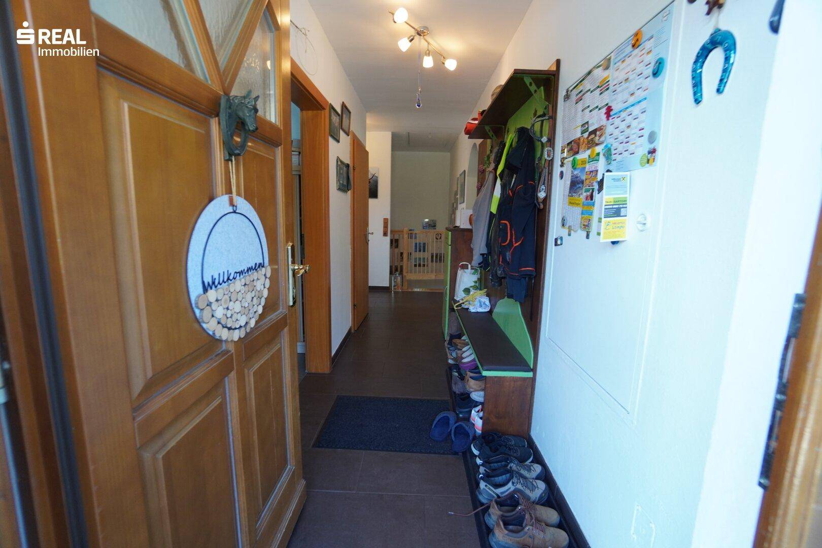 Heller Eingangsbereich mit Garderobe und Holzvertäfelung, führt zu weiteren Räumen.