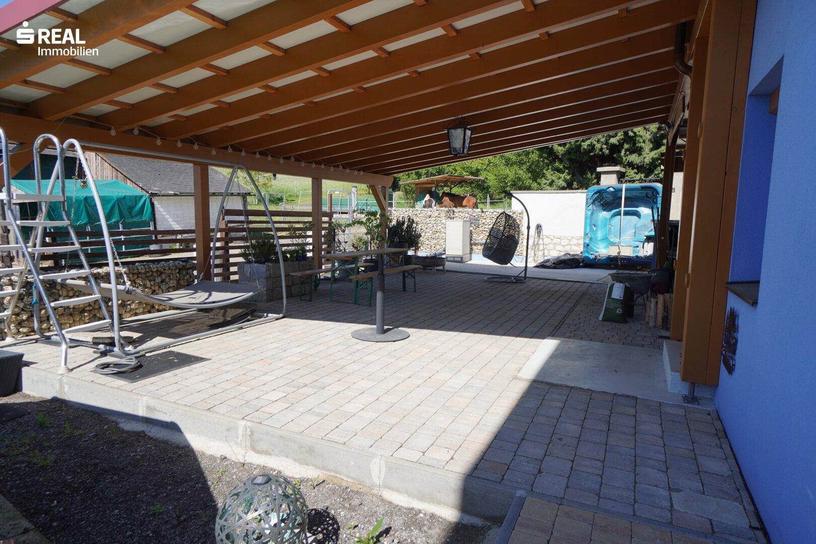 Überdachte Terrasse mit gepflastertem Boden und Schaukelstuhl, ideal für Entspannung im Freien.