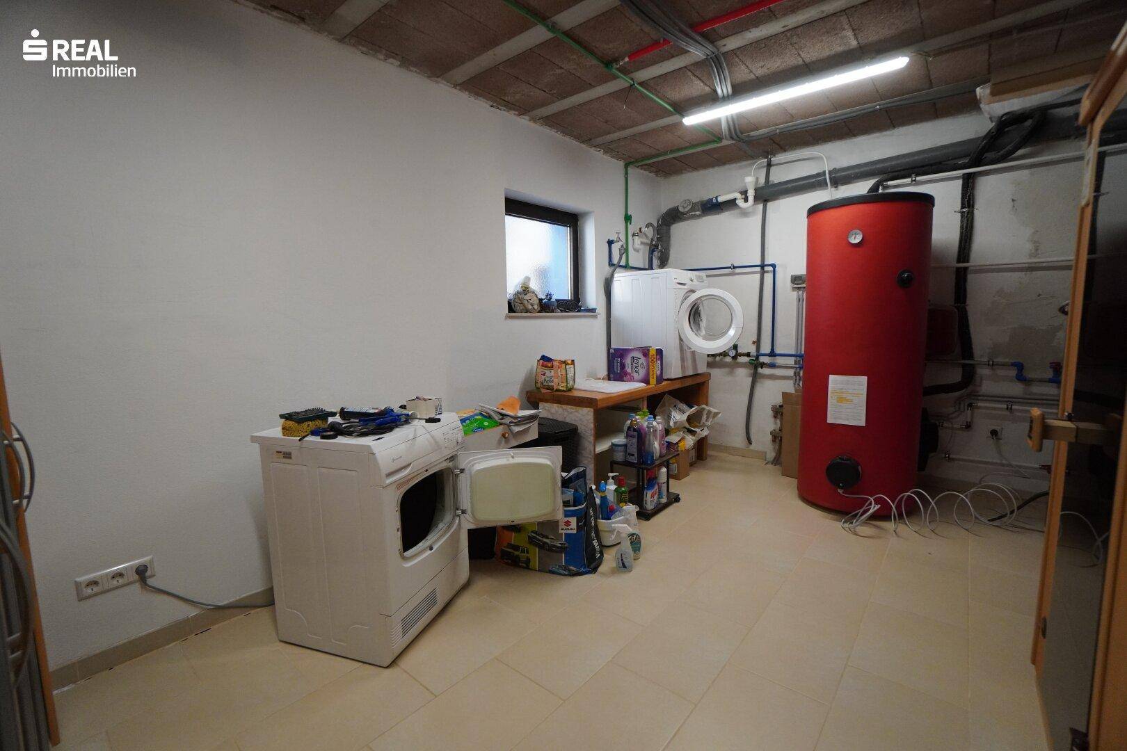 Praktischer Hauswirtschaftsraum mit Waschmaschine, Trockner und Warmwasserspeicher.