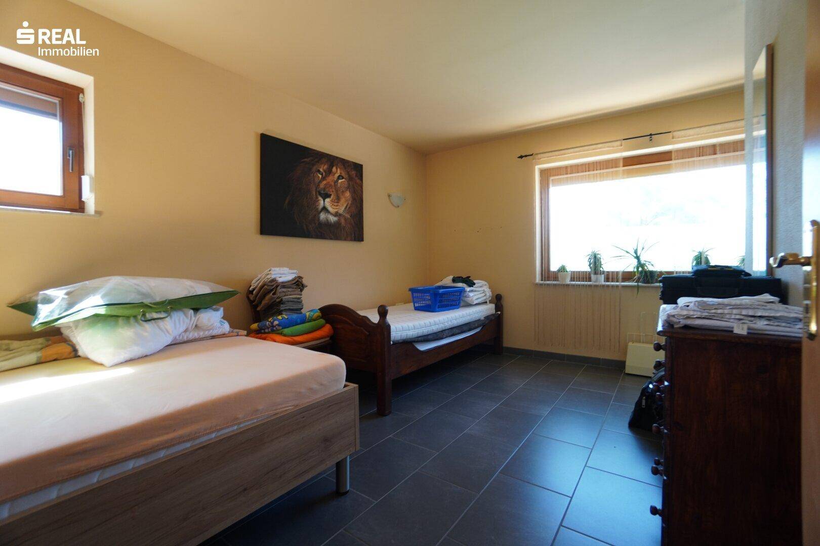 Geräumiges Schlafzimmer mit zwei Einzelbetten und dunklem Fliesenboden.