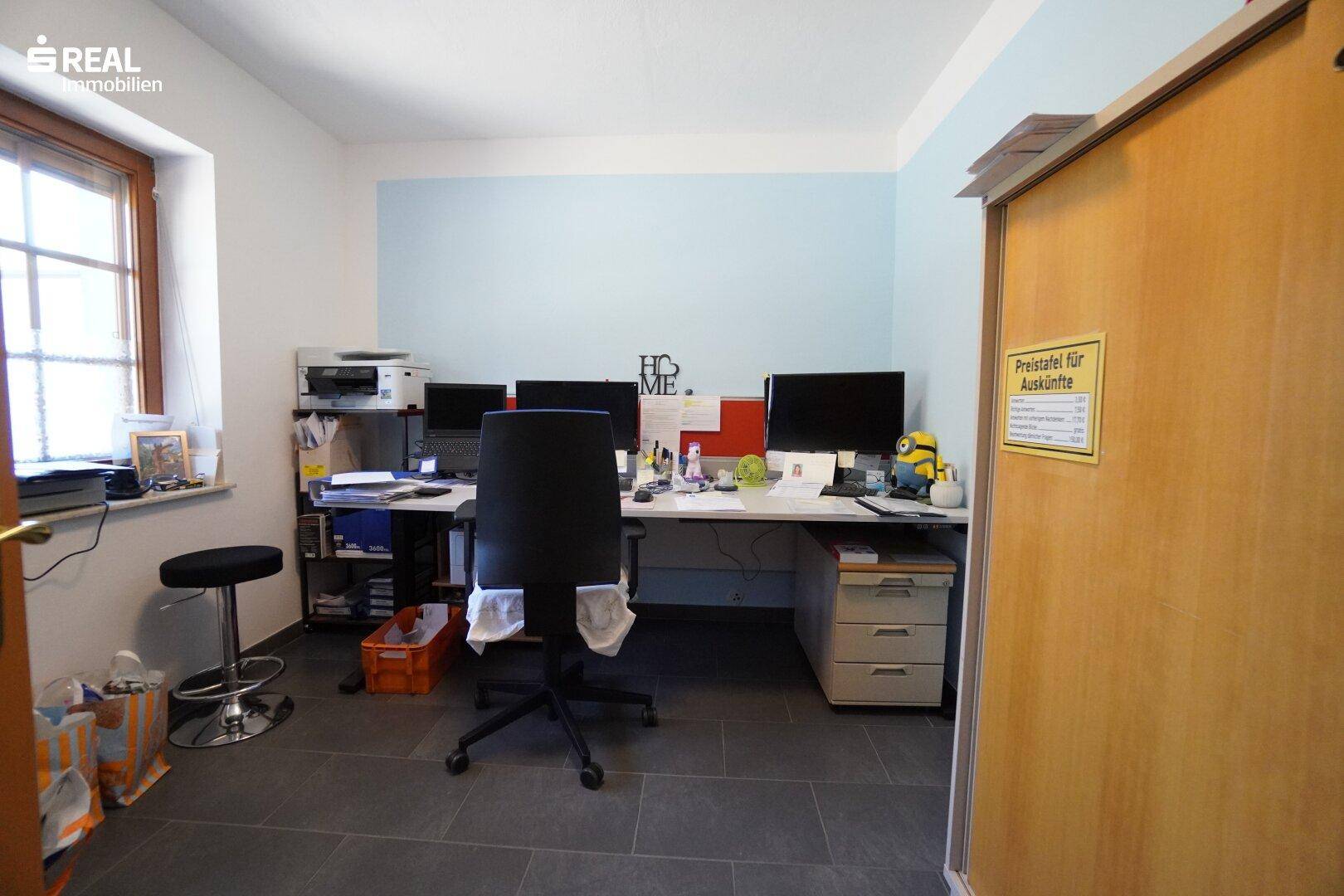 Helles Büro mit großem Schreibtisch, Computern und Fenster für Tageslicht.