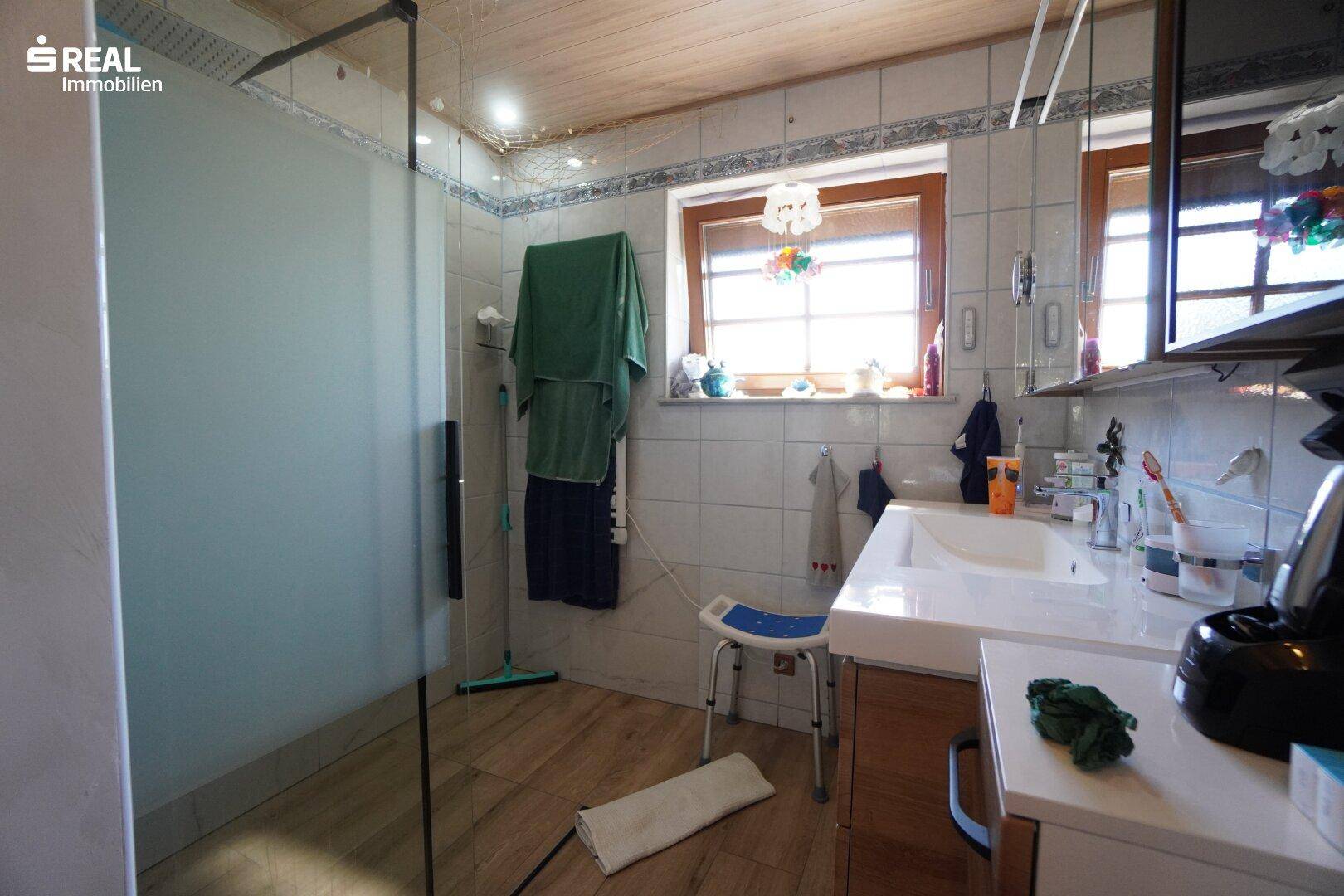 Modernes Badezimmer mit begehbarer Dusche, Waschbecken und Holzdecke.