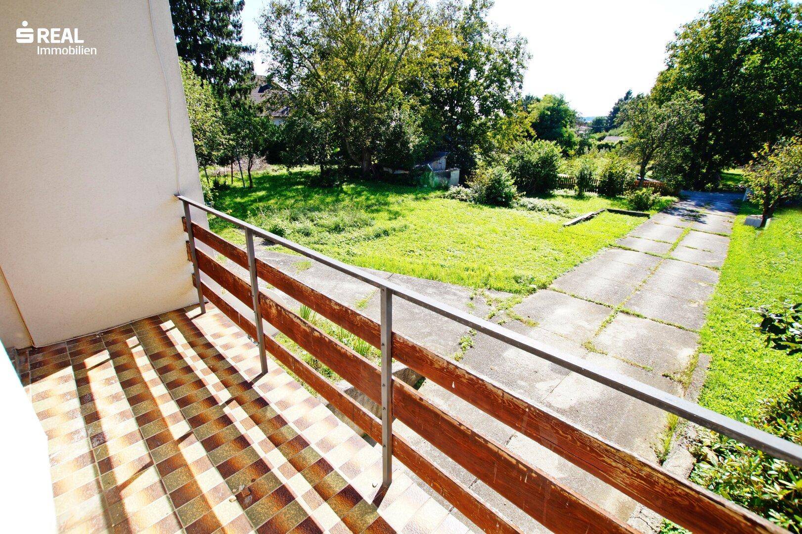 Balkon mit gefliestem Boden und Holzgeländer bietet einen weiten Blick ins Grüne.