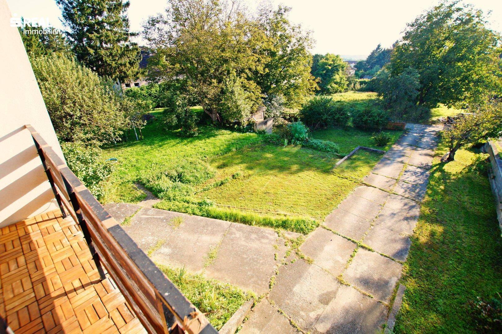 Weitläufiger Ausblick vom Balkon über den großen, unberührten Garten und die umliegende Landschaft.