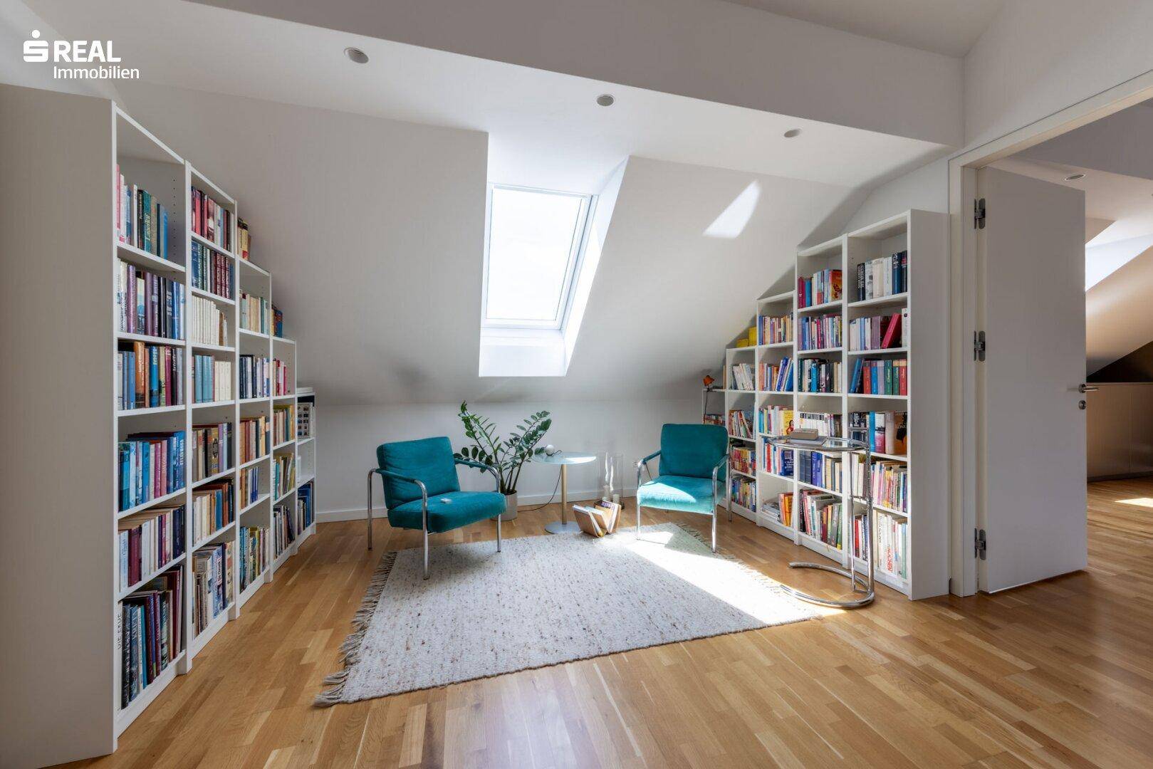 Gemütliche Bibliothek im Dachgeschoss mit Einbauregalen, Lesesesseln und Dachfenster.