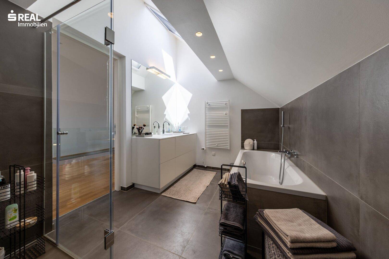 Geräumiges Badezimmer mit Badewanne, Dusche, Doppelwaschbecken und beheiztem Handtuchhalter.