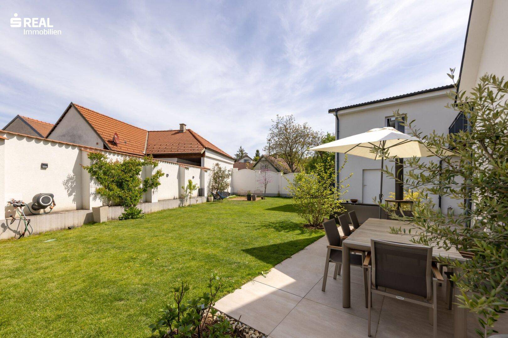 Großer, gepflegter Garten mit Rasenfläche und Essbereich im Freien.