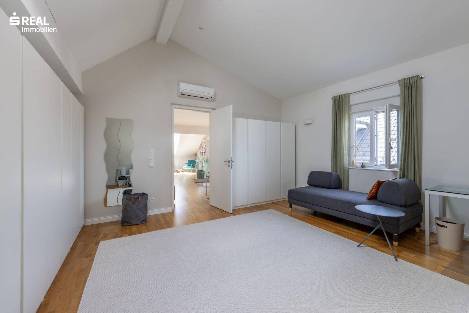 Geräumiges Schlafzimmer mit Einbauschränken, Holzboden und viel Tageslicht.