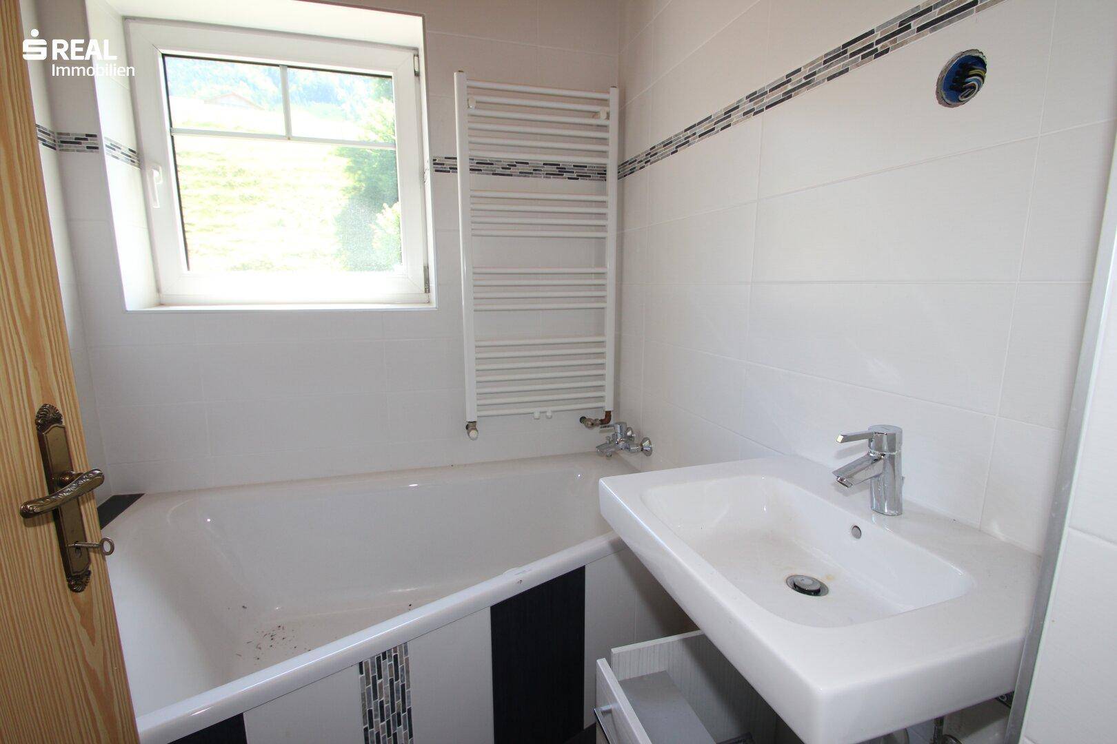 Modernisiertes Badezimmer mit Badewanne, Waschbecken und beheiztem Handtuchhalter.