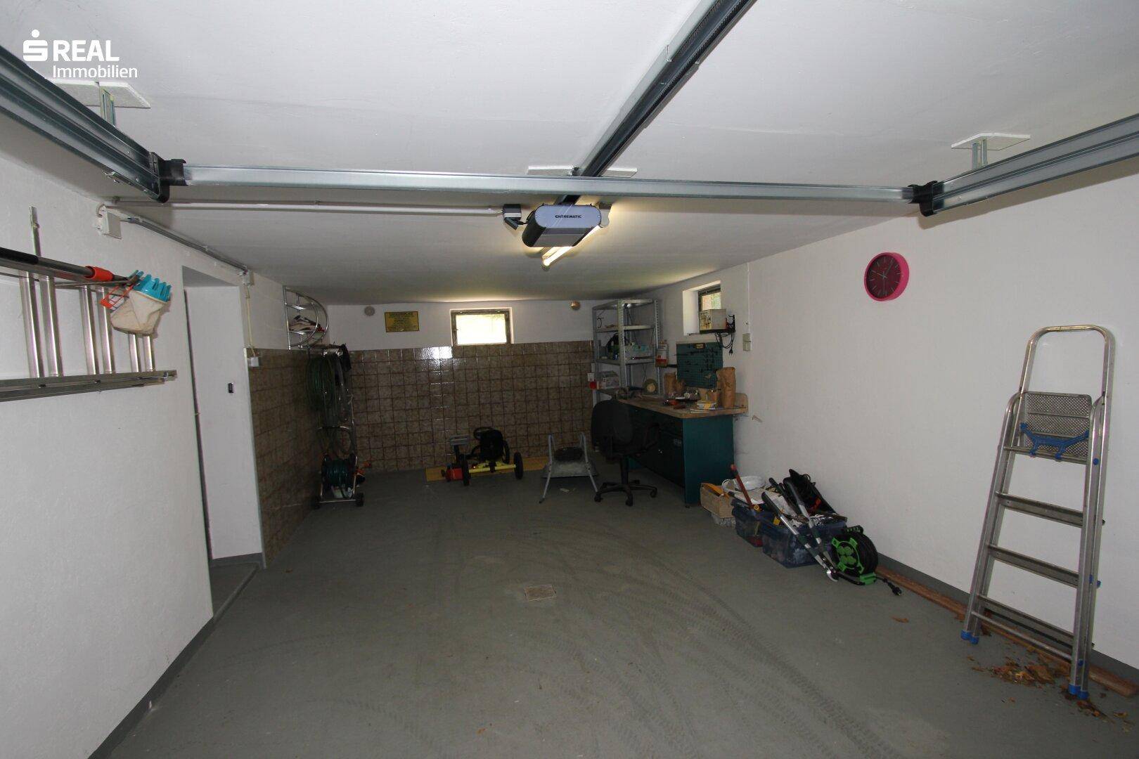 Große Garage mit viel Platz für Fahrzeuge und Lagerung, gut beleuchtet.