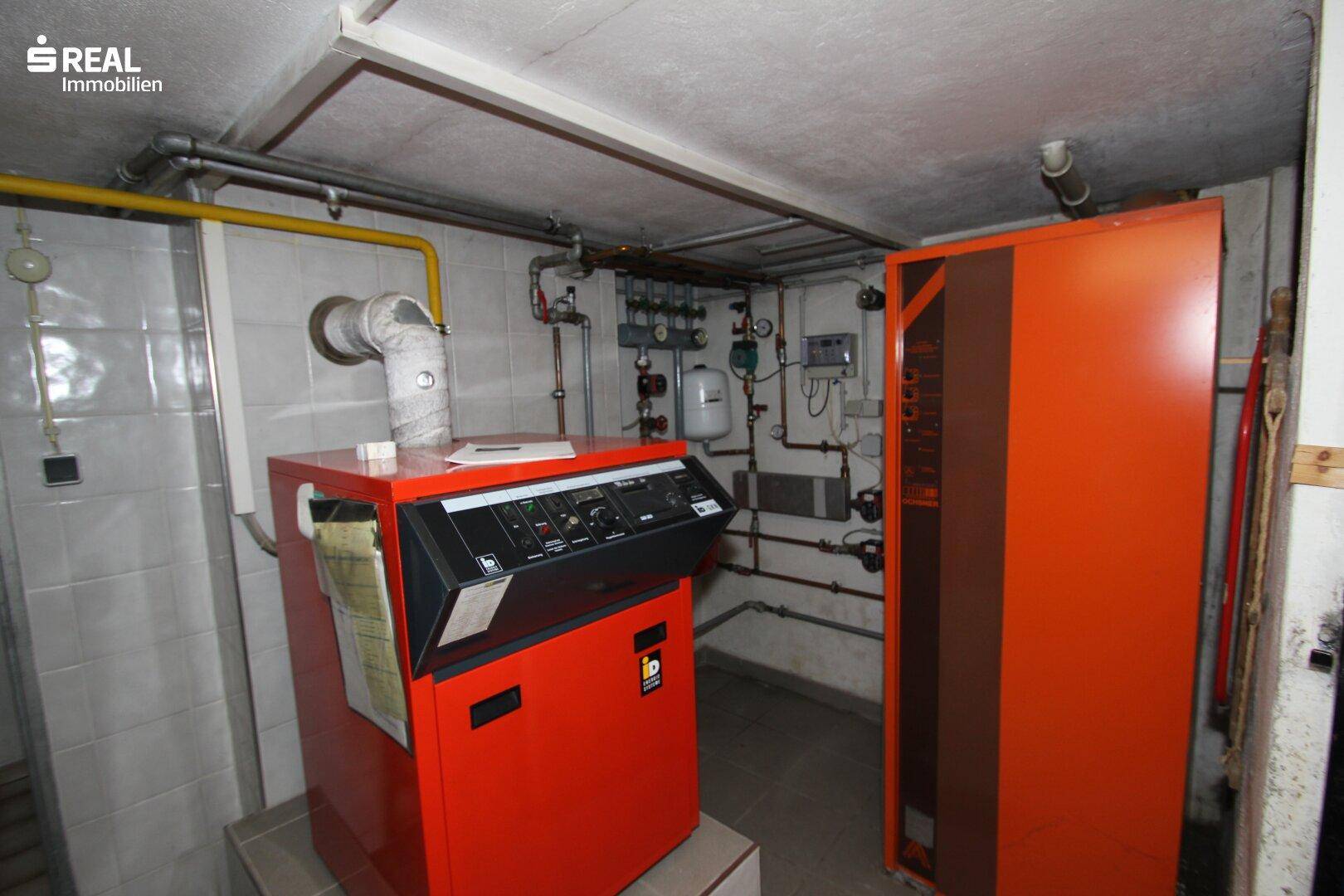 Heizungsraum im Keller mit großem Heizkessel und sichtbaren Installationen.